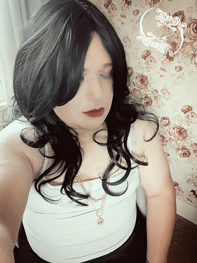 Mistress Ilya is looking away from the camera while taking a selfie.