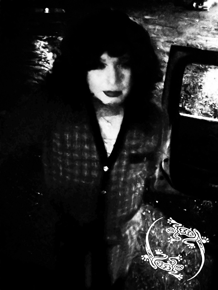 Mistress Ilya is standing on a street. There is no color in the photo.