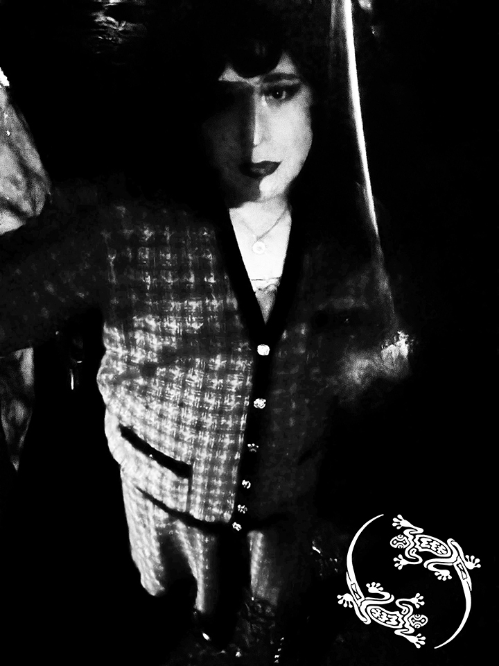 Mistress Ilya is standing on a street. There is no color in the photo.