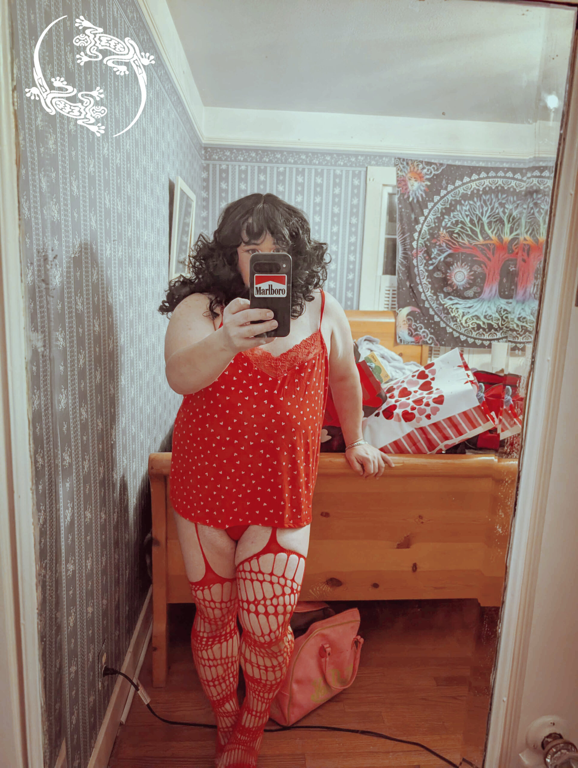 Mistress Ilya is standing in front of a mirror in a night shirt and stockings.