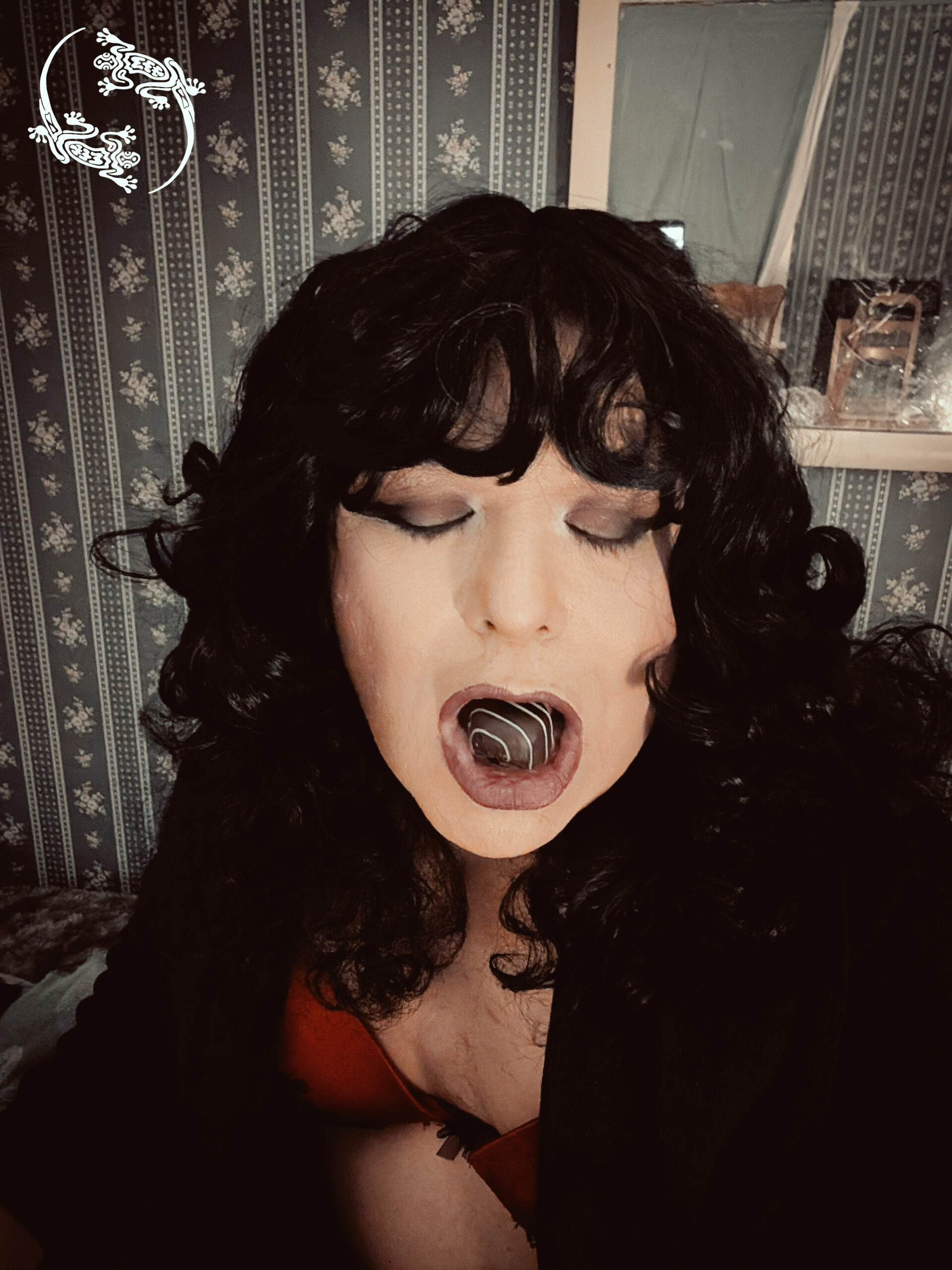 Mistress Ilya has a piece of chocolate candy in her mouth.