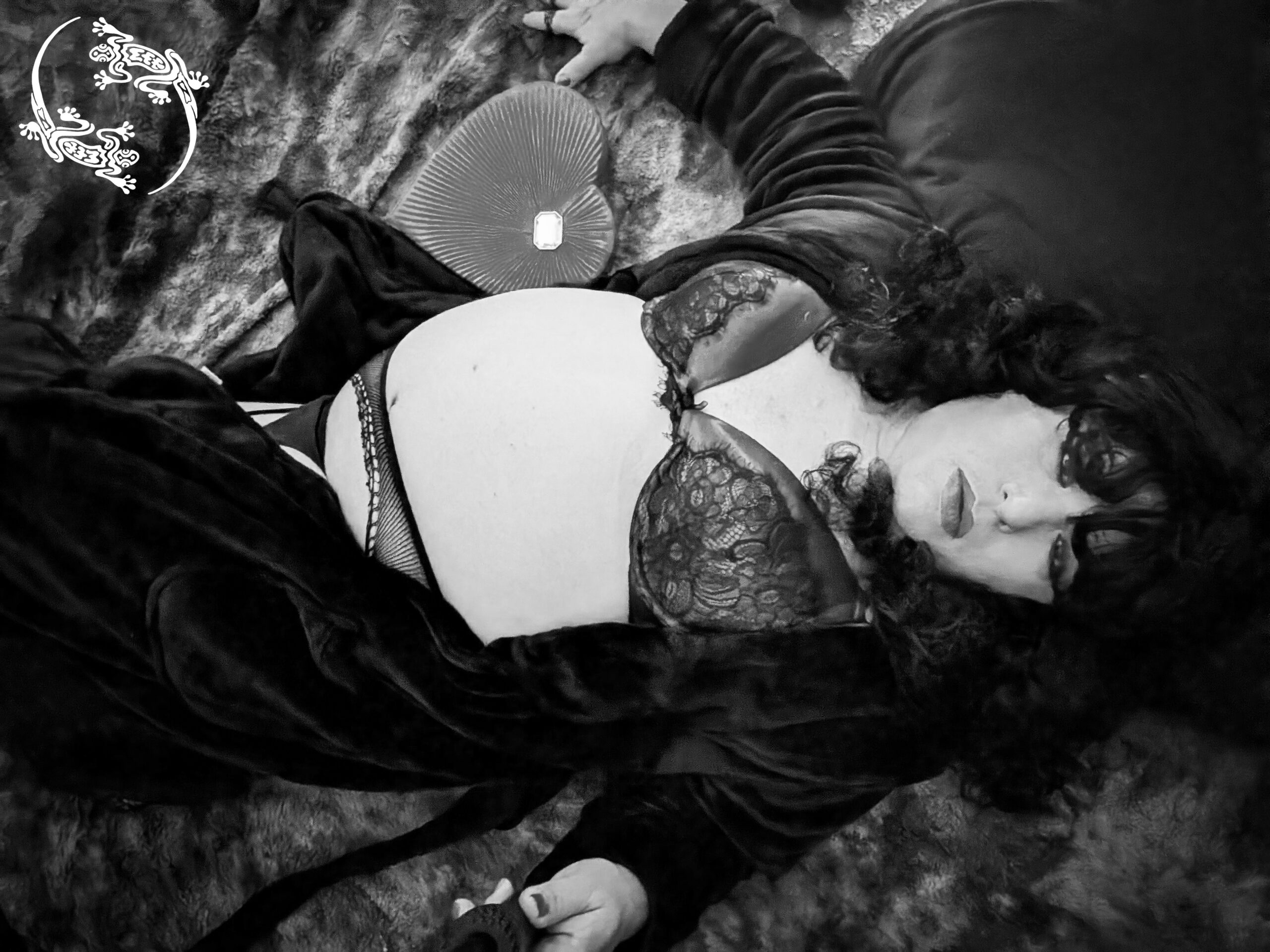 Mistress Ilya is laying on her bed looking up. There is a box of chocolates next to her.