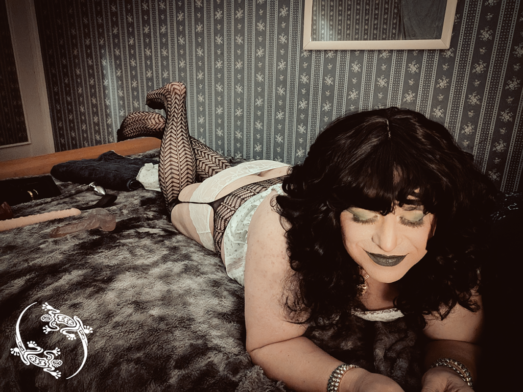 Mistress Ilya is laying on her stomach with her eyes closed. 