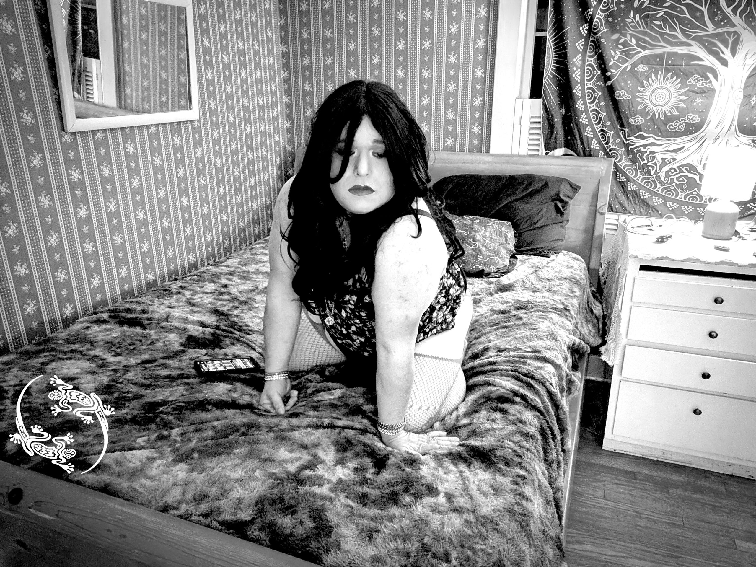 Mistress Ilya is looking away while on all fours on her bed.