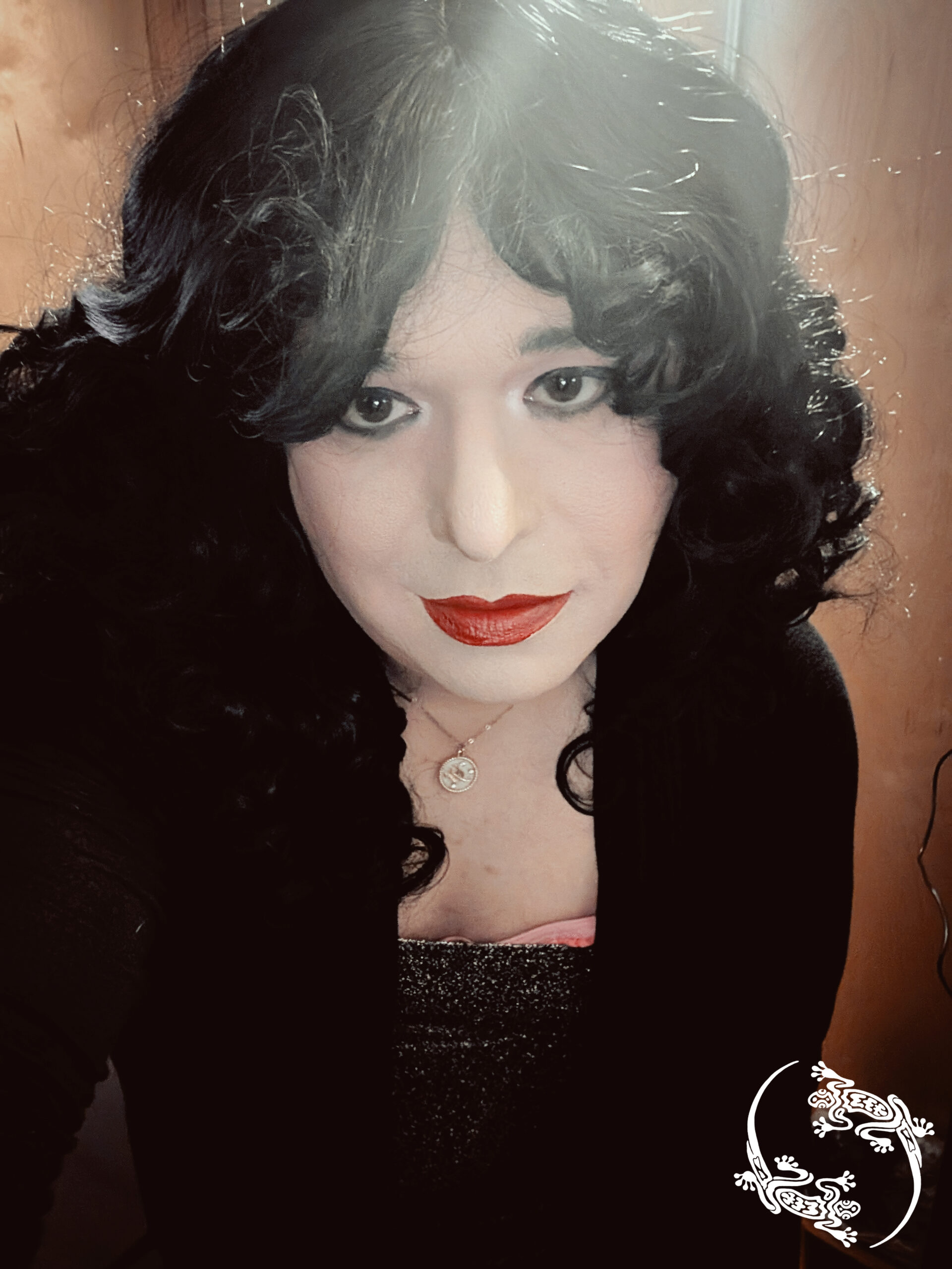 Mistress Ilya is looking into the camera while a light is overhead.