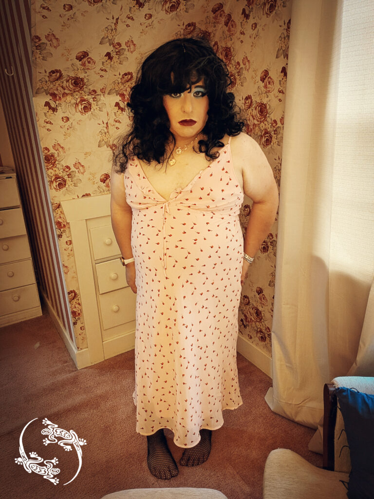 Mistress Ilya is posing in a sundress in her bedroom.