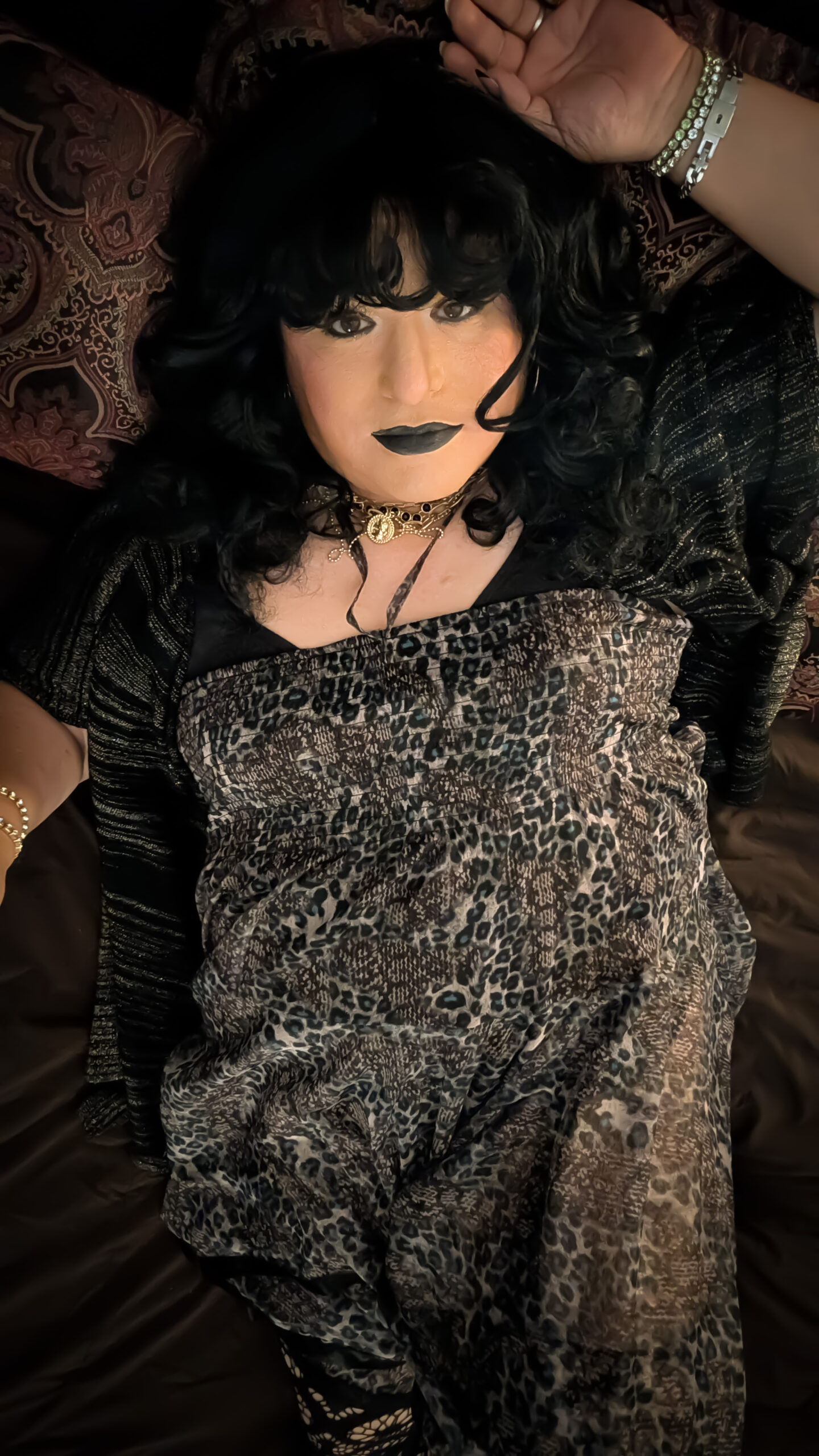 Mistress Ilya is wearing a dress and laying on her bed. 