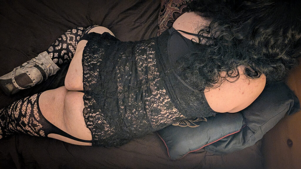 Mistress Ilya is laying on her stomach on her bed.