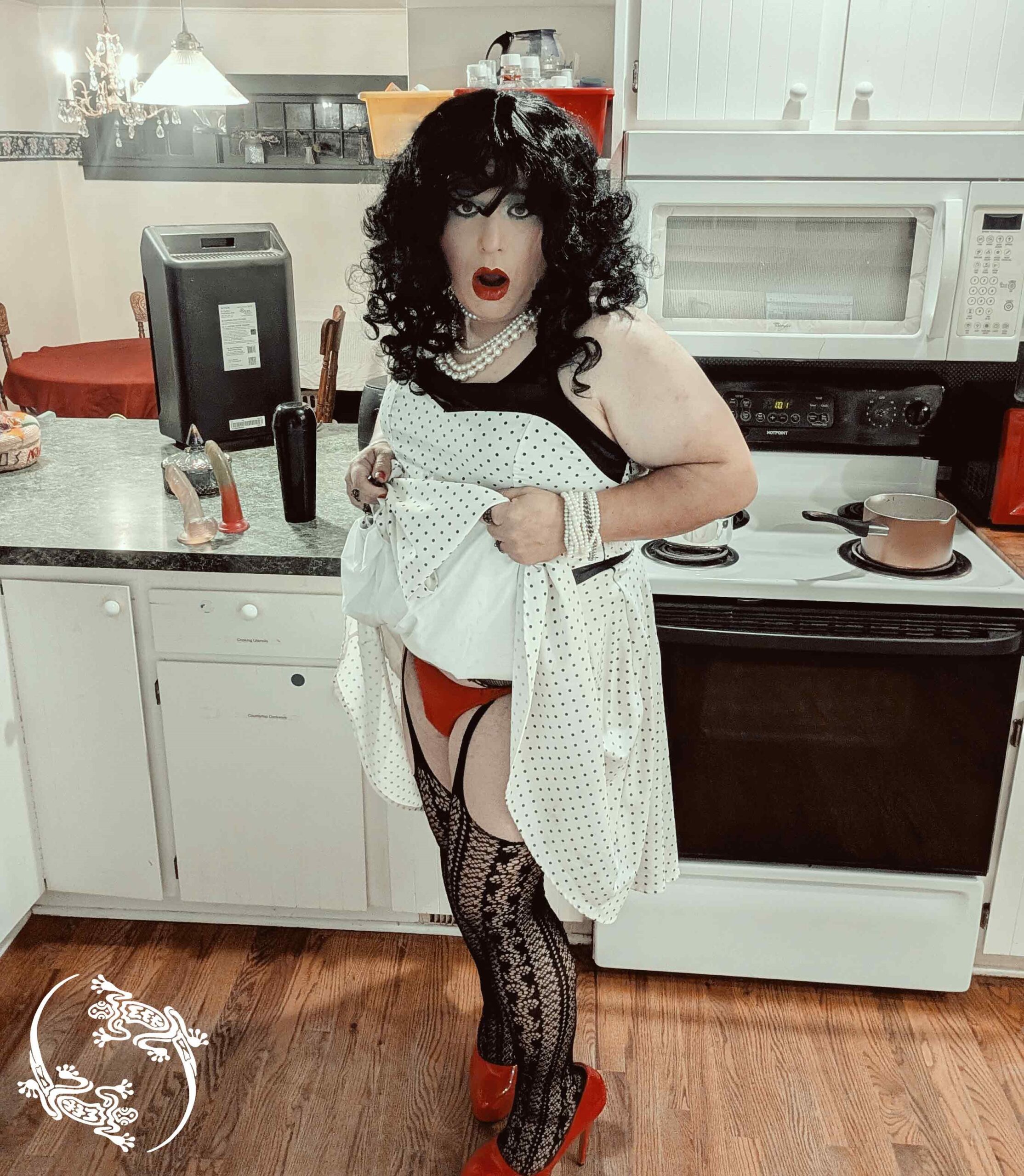 Mistress Ilya is in her kitchen lifting up her skirt to show a thong and stockings underneath. 