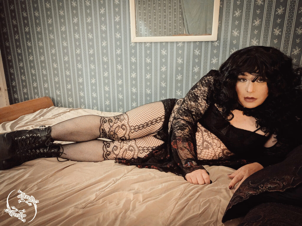 Mistress Ilya is laying on her bed on her side to look at the camera.