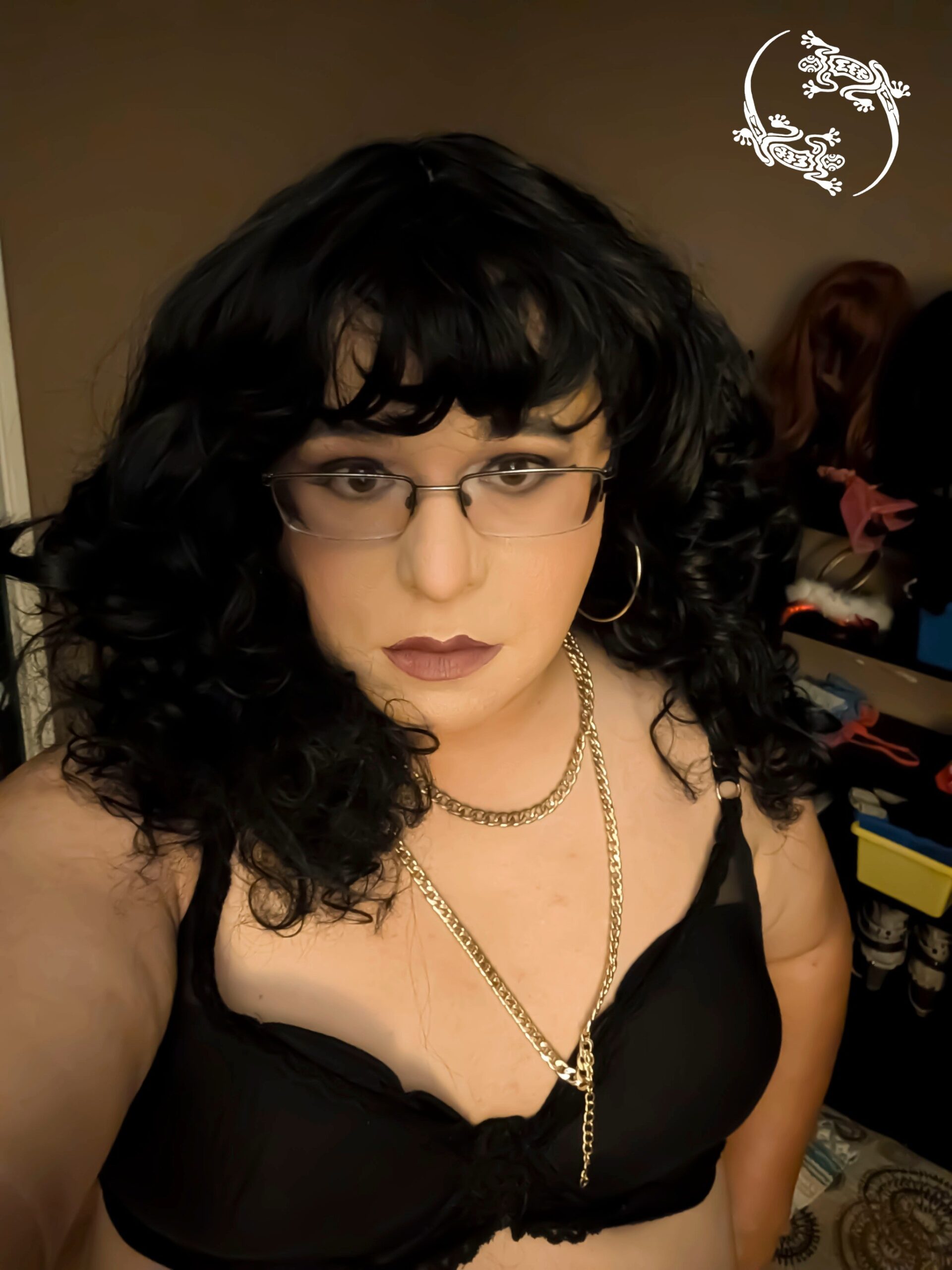 Mistress Ilya is wearing a bra and glasses and is looking into the camera.